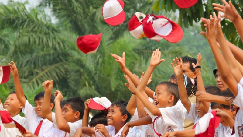 Tanoto Foundation Children celebrate by throwing caps in the air.